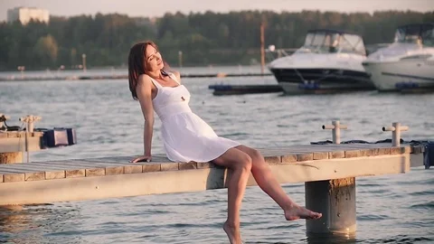 Woman walks on wooden pier in a summer day after jogging and dives into the Stock Footage