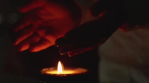 Woman wants her hands to be over a burning candle in close-up. the concept of Stock Footage 261151053