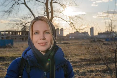A woman in a warm jacket in the rays of backlight during sunset against the b Stock Photos
