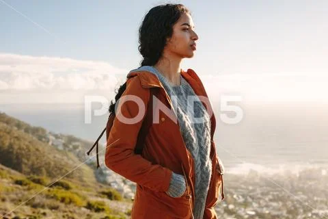 Woman in warm wear standing on a mountain looking away Stock Photos