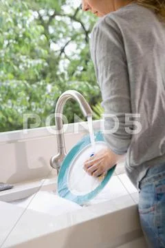 Woman Washes Plate At Sink