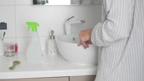 A woman washes a white sink in the bathroom with a sponge Stock Footage 161457053
