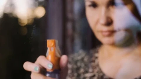 A woman washes a window in the rays of the setting sun. Stock Footage 76990208