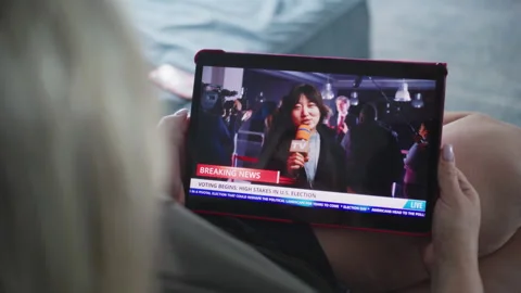 Woman watches news report about US elections using digital tablet Stock Footage 279816590