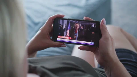 Woman watching news report about the US elections using mobile phone Stock Footage 279817287