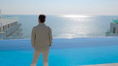 Woman watching the ocean from an infinity pool at a luxury hotel Stock Footage 344313383