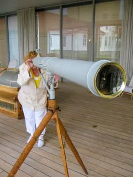 A woman is watching something in the distance through a ship's old spyglass Stock Photos