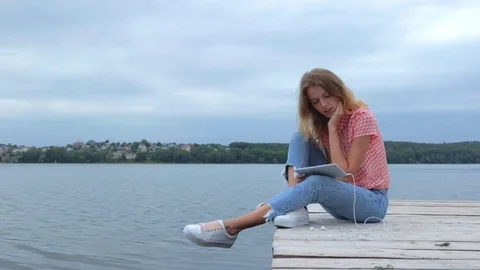 Woman watching at tablet while sitting near lake Stock Footage 91726150