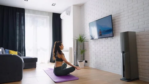 Woman watching yoga tutorial and sitting in lotus pose 動画素材 158182390