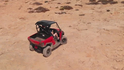 Woman waves at camera while riding in a four wheeler dune buggy in Cavo 動画素材 98407782