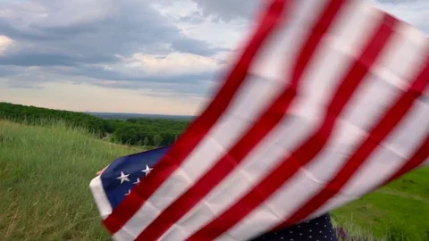 Woman waving a US flag is standing on top of a hill - the concept of Stock Footage