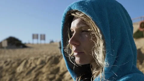 Woman wearing blue hooded top on beach Stock Footage