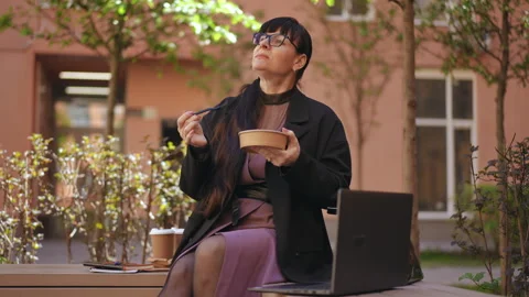 A woman wearing eyeglasses eats, while holding a plastic fork Stock Footage 282454422