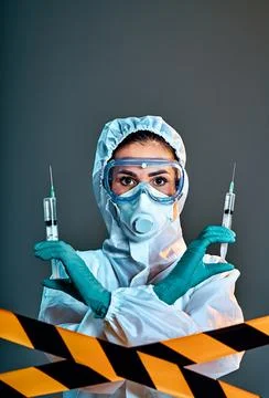 Woman wearing gloves with biohazard protective suit and mask holds an virus v Stock Photos