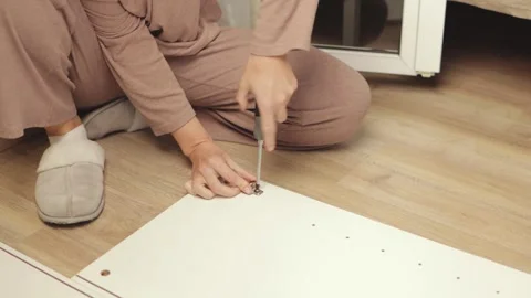 Woman wearing home clothes assembling flat pack furniture, tightening screw.. Stock Footage 303844052