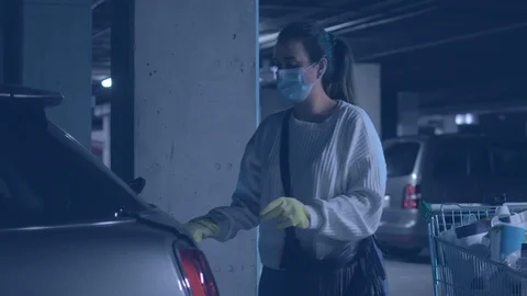 Woman wearing mask and gloves keeping the shopping basket in her car trunk Stock Footage