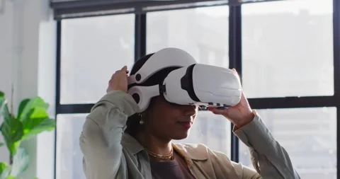 Woman wearing VR headset testing virtual demo in bright office loft, adjusting Stock Footage 345839914
