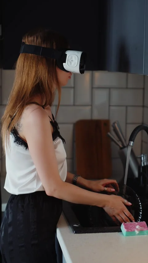 Woman Wearing VR Headset While Washing Dishes in Kitchen 스톡 동영상 323090573