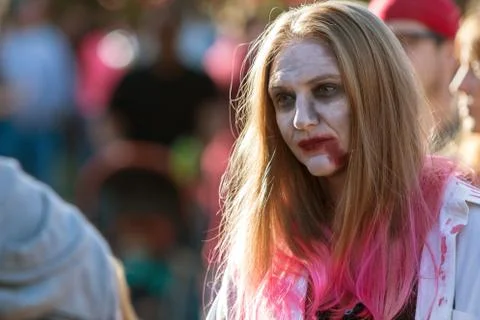 Woman Wearing Zombie Makeup Wanders Through Crowd At Halloween Festival Foto stock