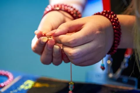 A woman weaves ruby bracelets 库存照片