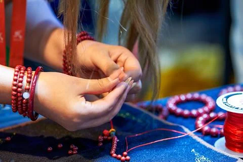 A woman weaves ruby bracelets 库存照片