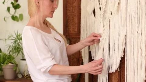 Woman weaving macrame from light threads in a home workshop. Stock Footage 154342671