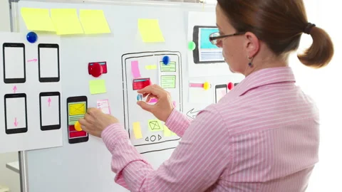 Woman web designer is developing an application for mobile phones.  Stock Footage 160611472