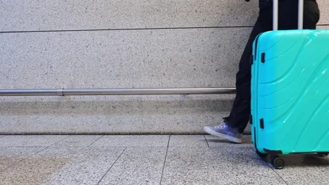 Woman wheeling a teal hard-shell suitcase along the airport area, travel de.. 库存影片 342065268