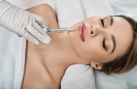 Woman while procedure lip augmentation at cosmetology clinic with beautician. Photos