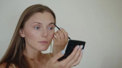 A woman while using eyebrow pencil for apply color to her eyebrows. Self makeup 스톡 동영상 282594447