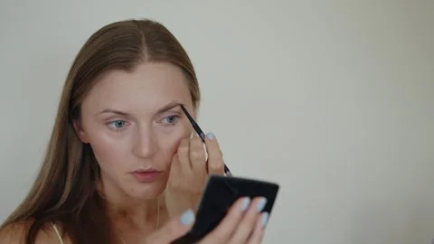 A woman while using eyebrow pencil for apply color to her eyebrows. Self makeup 스톡 동영상 289398680