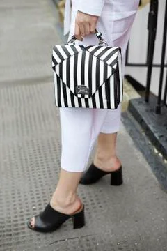 Woman in white culottes holding striped handbag, low section Stock Photos