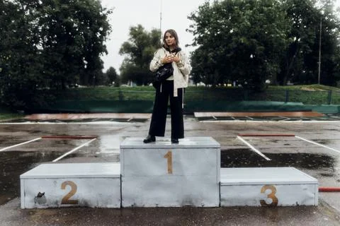 A woman in a white jacket stands on the podium in the rain Stock Photos