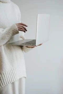 Woman in white pullover using laptop computer over white wall. Web, internet, Stock Photos