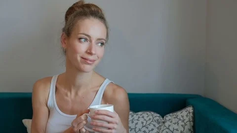 A woman in a white shirt holding a cup and looking at with interest Stock Footage