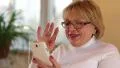 Woman with white smartphone speaks smiling, laughs and gesticulates HD Footage