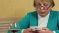 Woman with white smartphone writes sms and drinks brandy HD Footage