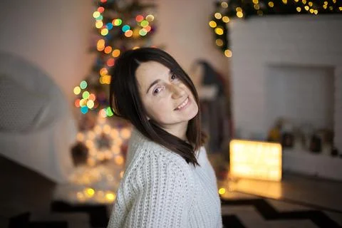 A woman in white sweater smiling and in front of christmas tree Stock Photos
