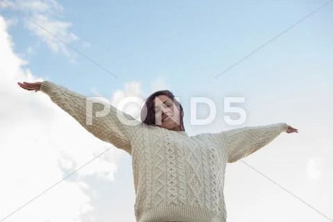 Woman in white sweater stretching her arms against sky Stock-Fotos