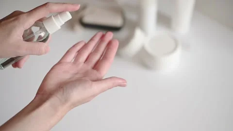 Woman at the white table with cosmetics set splashes hand lotion. Cosmetic 動画素材 138784342