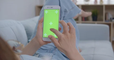 Woman In White Top Laying On Sofa Uses Smartphone With Green Screen Stock Footage