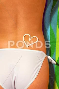 Lower half of a woman sunbathing wearing white bikini bottoms with