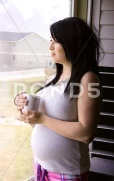 Woman by the window with a cup of coffee Stock Photos