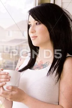 Woman by the window with a cup of coffee Stock Photos