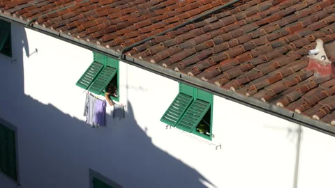 Woman at window pulling the laundry in the house, Italy, 4K, DNxHR Stock Footage 156541234