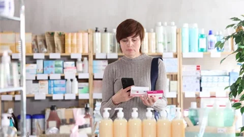 Woman in winter clothes scans code on package of paracetamol pills to check the Stock Footage 312627497