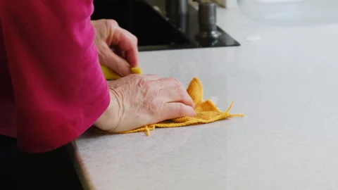 Woman wipes kitchen surface using yellow microfiber cloth Stock Footage 316172336