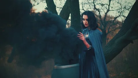 Woman witch, hand waving casting spell Magical black thick smoke fog from vat 4k Stock Footage 234615625