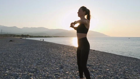 A woman without makeup doing a workout on a pebble beach near the sea. Portrait Stock Footage 117369893