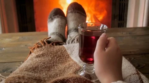 Woman in wool socks relaxing by the fireside at house with cup of hot tea Stock Footage